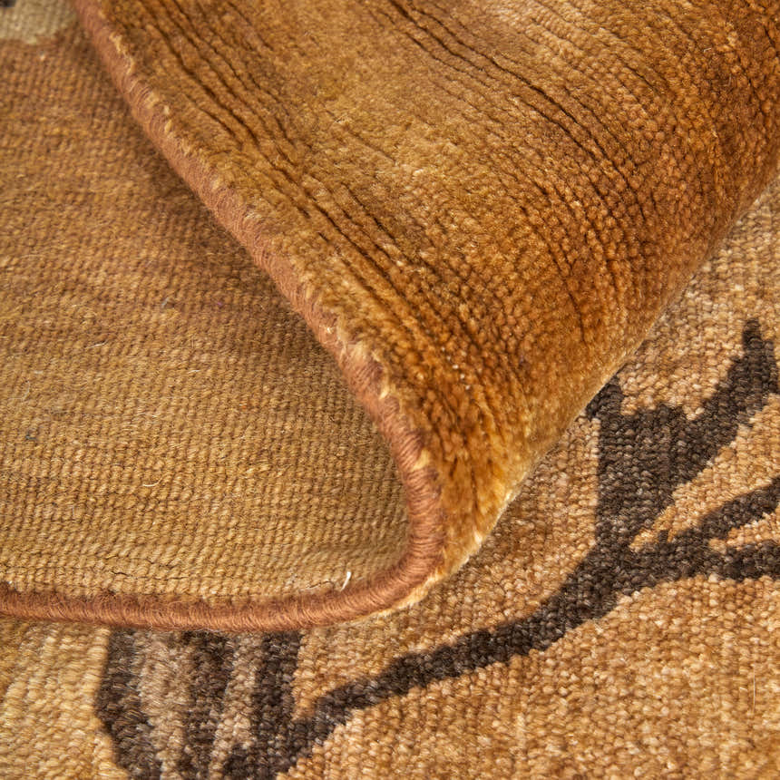 Close-up of the hand-knotted Feizy Cordonnet rug. Brown and orange wool rug with a floral and botanical pattern. Fold