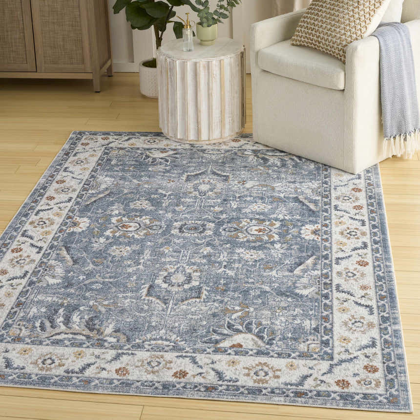 Living room scene with a blue vintage Nourison Astra area rug, white armchair, and light wood accents.