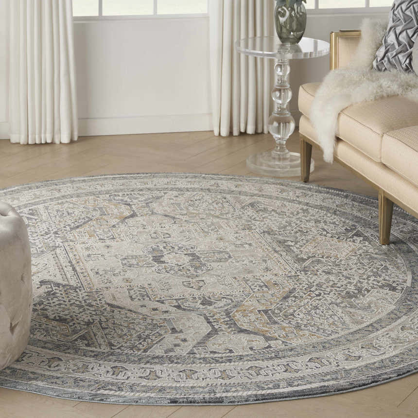 Living room scene with a round Nourison Lynx Ivory Charcoal Vintage Area Rug, beige sofa, and glass table.