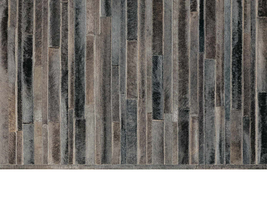 Close-up of the Calvin Klein Home Prairie Black rug. Handmade hair on hide rug with vertical stripes in shades of black and gray.
