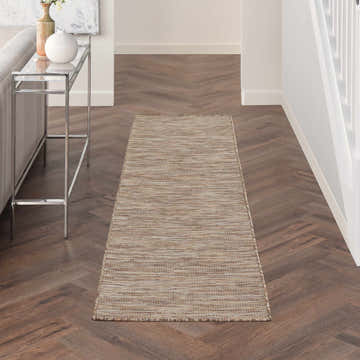 Hallway scene with Nourison Positano Beige runner rug on herringbone wood floor. Modern console table with vases.