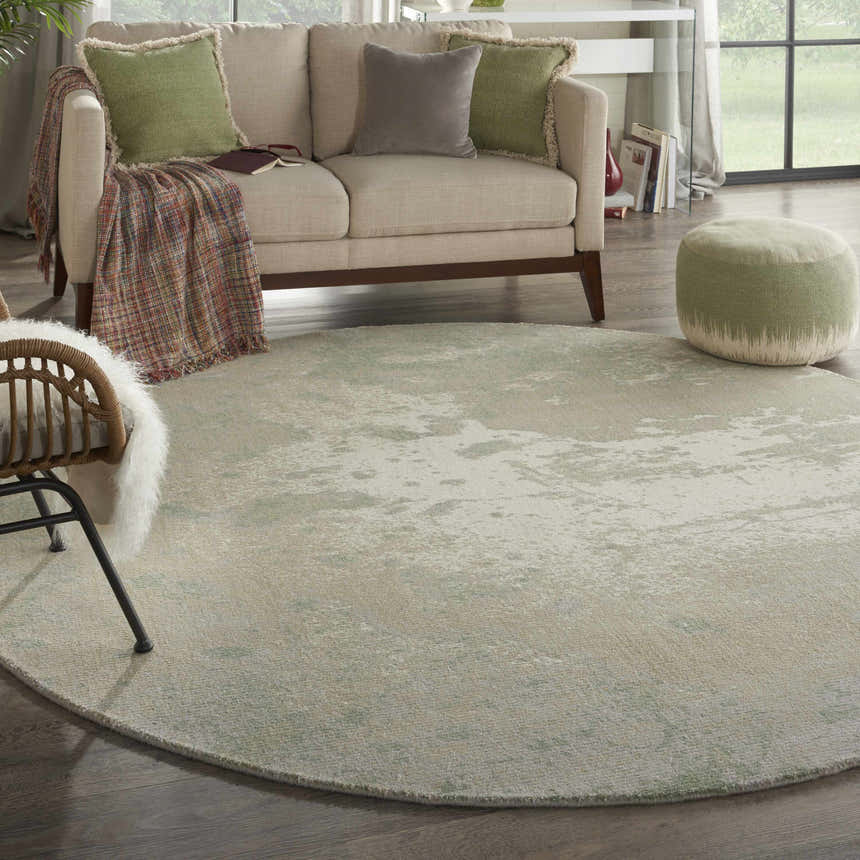 Living room scene with a round Nourison Twilight Ivory Green rug, sofa, and green ottoman.
