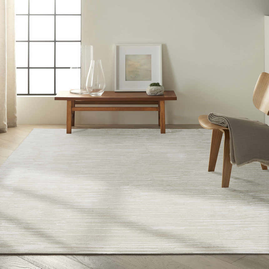 Minimalist room with a Calvin Klein CK010 Linear Ivory rug, wood bench, and chair. Neutral tones, modern style.