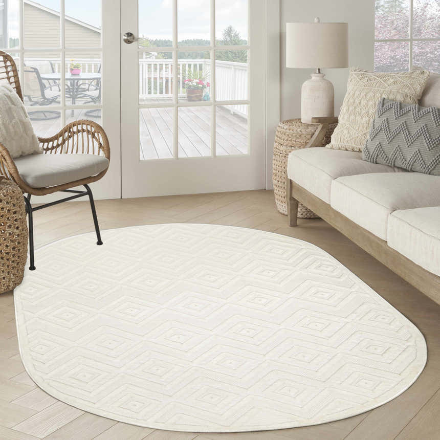 Sunlit living room with a Nourison Versatile Ivory White rug, sofa, and wicker chair. Modern, neutral tones.