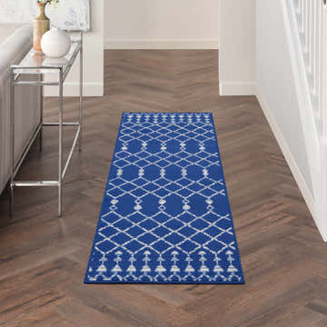 Hallway with Nourison Whimsicle Navy Bohemian runner rug on herringbone wood floor. Console table with vases.