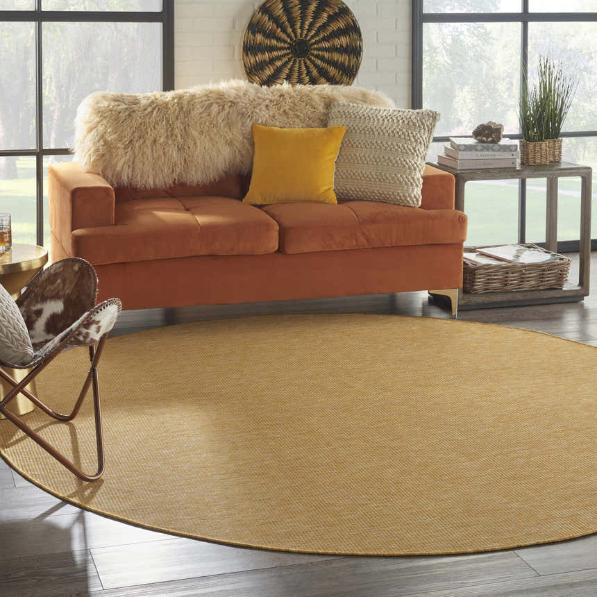 Living room scene with a round Nourison Positano Yellow rug, orange sofa, and mid-century modern decor.