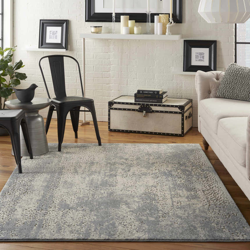 Living room scene with a Nourison Sahara Ivory/Slate rug, sofa, black chairs, and white brick wall.