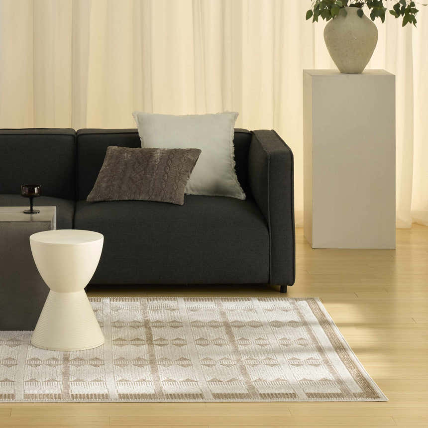 Modern living room scene with a Nourison Nordic Taupe rug, gray sofa, and ivory accents.