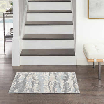 Entryway scene with Nourison Divine Aqua rug, white stairs, dark wood floor, and modern white bench.