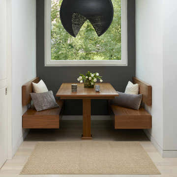 Breakfast nook with wood benches and a Nourison Tulum Taupe Outdoor Area Rug on light wood floors.