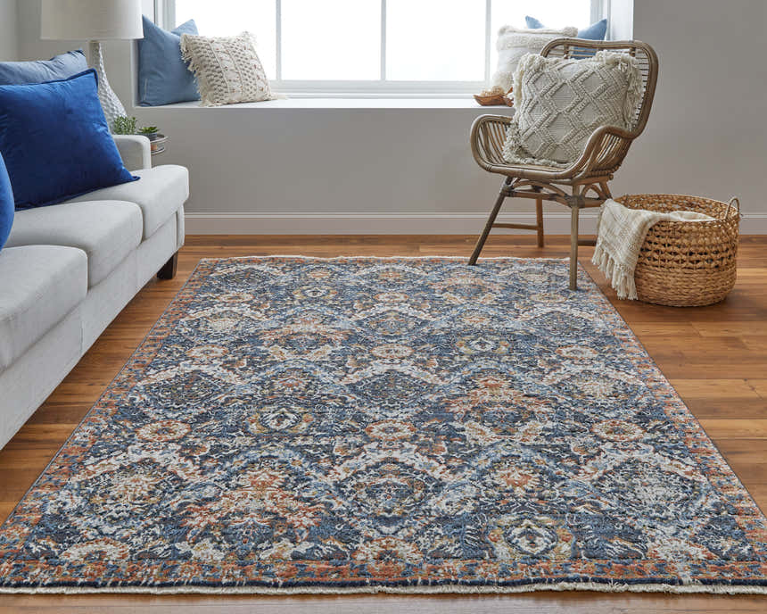 Living room scene with the Feizy Kaia rug in blue, orange, and ivory. Features a sofa, chair, and wood floors. Roomscene-Rectangle