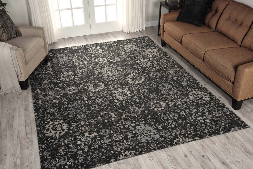 Living room scene with a Nourison Twilight Onyx Persian rug, tan sofa and armchair, and light wood floors.