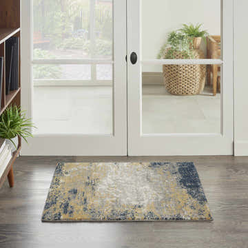 Entryway scene with Nourison Twilight Navy Gold rug on wood floor, white doors to patio, and bookshelf.