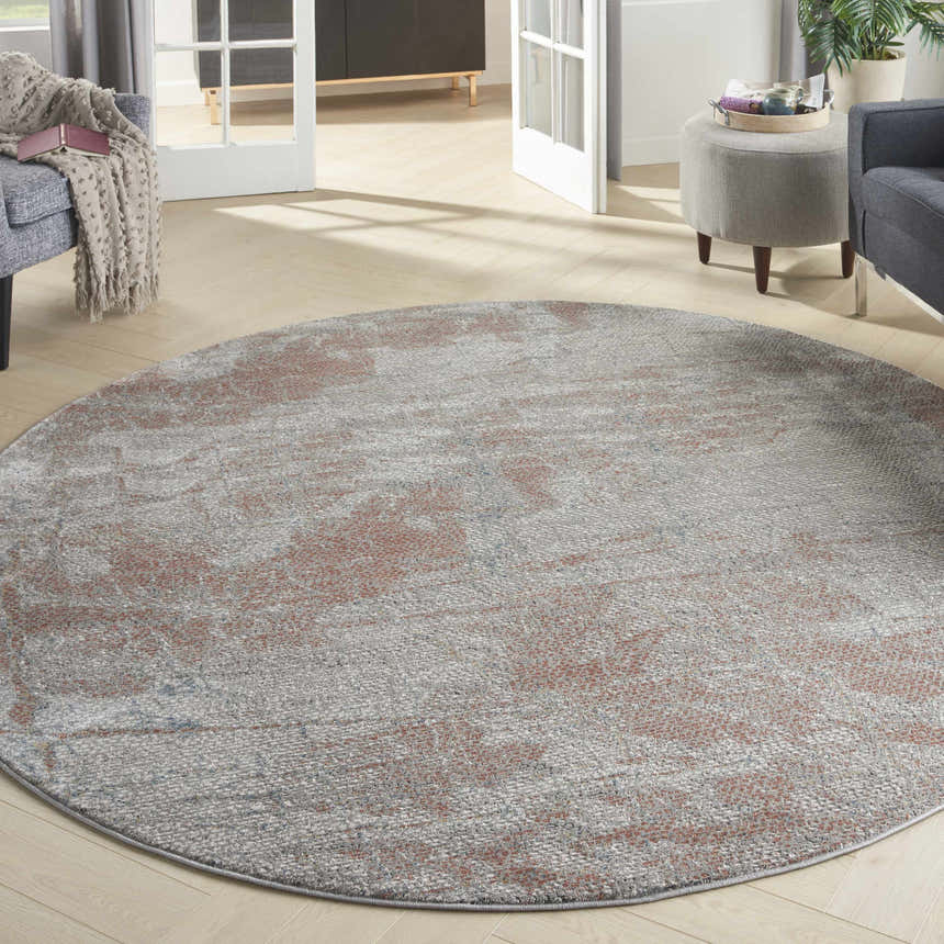 Modern living room with a round Nourison Rustic Textures Light Grey Rust rug, gray sofa and ottoman.