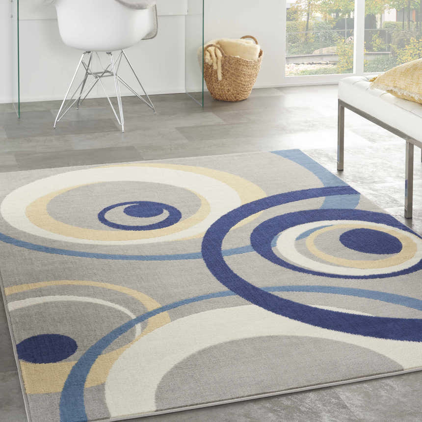 Minimalist room with the Nourison Grafix Grey rug featuring blue, white, and yellow concentric circles.