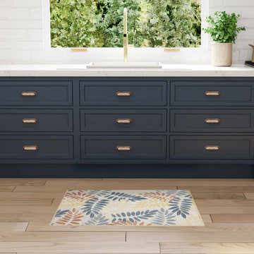 Modern kitchen with blue cabinets and Nourison Aloha Ivory Blue Area Rug on wood floor.