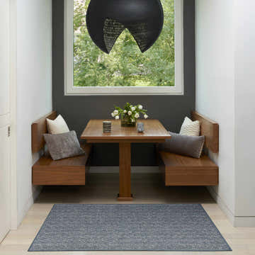 Breakfast nook with wood benches and a Nourison Tulum Denim Outdoor Area Rug on light wood floors.