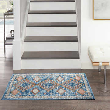Entryway with Nourison Quarry Blue Vintage rug, stairs, white bench, and dark wood floors.
