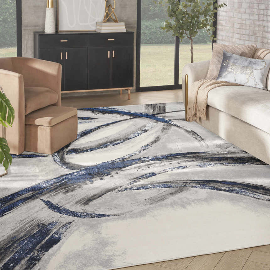 Living room scene with a Nourison Splash Grey Navy rug, beige sofa and chair, and modern decor.