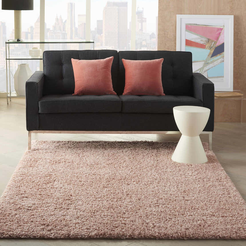 Living room scene with a Blush Shag rug, gray sofa, pink pillows, and a city view. Boutique Rugs.