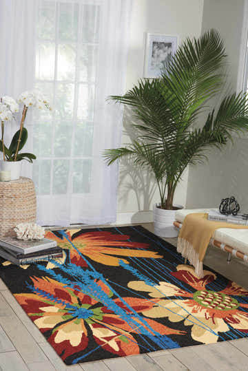 Living room scene with Nourison South Beach Black Area Rug. Floral design in red, orange, blue on a black rug. Modern style.