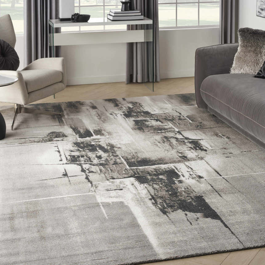 Living room scene with grey sofa and Nourison Twilight Grey Ivory Black rug, modern abstract design.