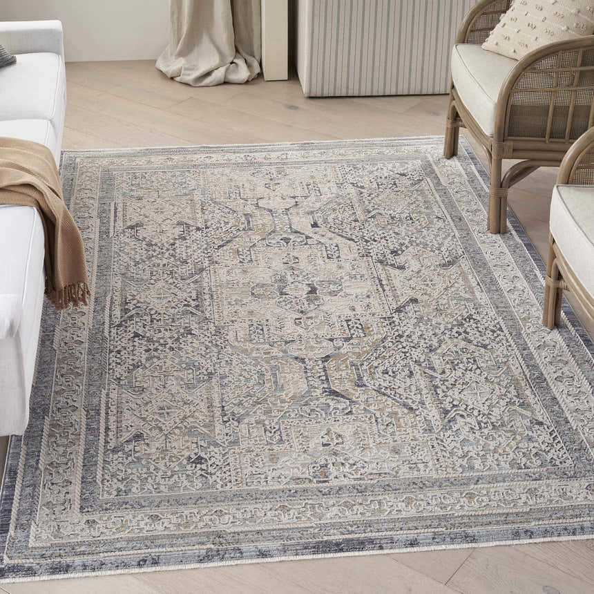 Living room scene with a Nourison Lynx Ivory Charcoal Vintage Area Rug, white sofa, and rattan chair.