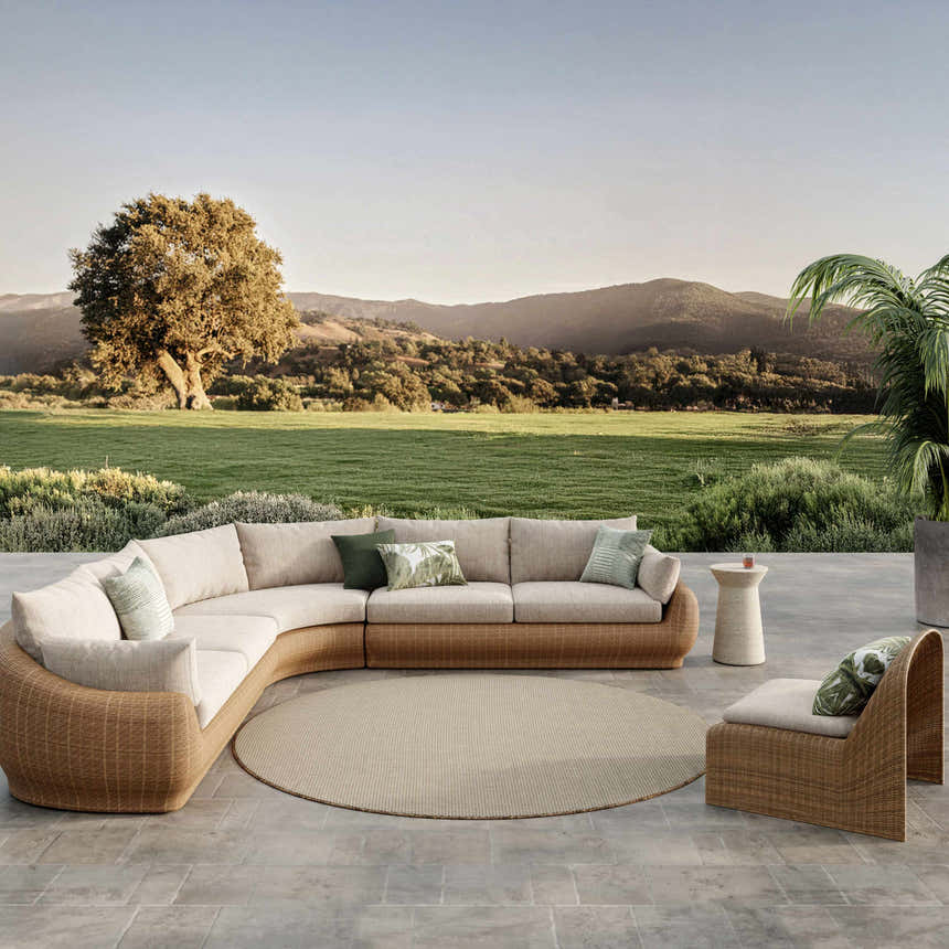 Outdoor patio scene with a round Nourison Courtyard Jute Ivory rug, wicker furniture, and scenic mountain view.