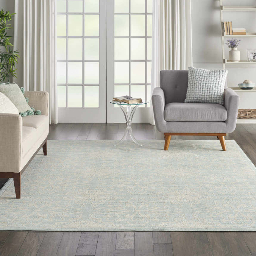 Living room with a Nourison Jubilant Ivory Green rug, light sofa, gray chair, and white french doors. Farmhouse style.