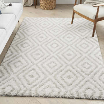 Living room scene with a Nourison Modern Shag Ivory Silver rug, white sofa, and wood-framed chair.