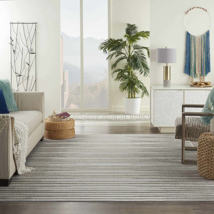 Living room scene with a light gray sofa and the Nourison Key Largo Light Grey Contemporary Area Rug.
