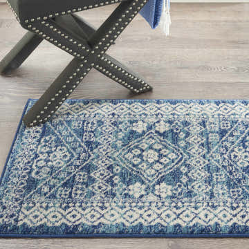 Close-up of Nourison Passion Navy Blue rug with bohemian pattern and gray studded stool on wood floor.