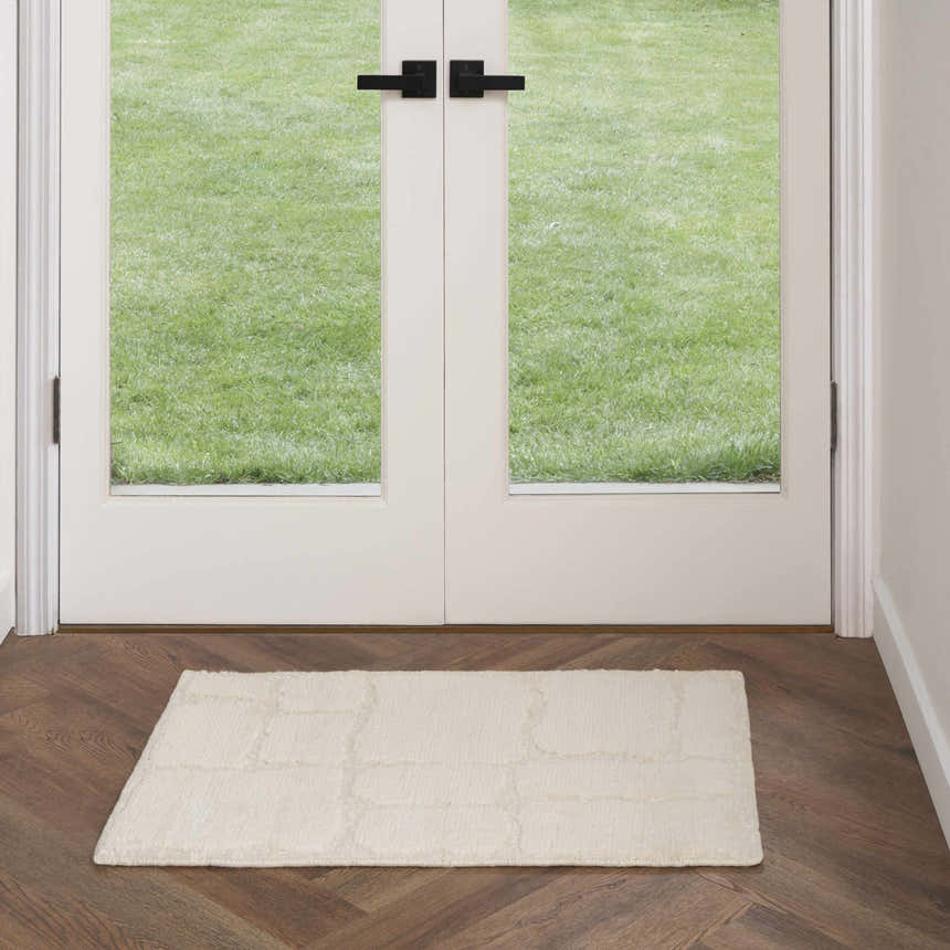 Entryway with herringbone wood floors and Nourison Blanco Ivory area rug in front of white doors.