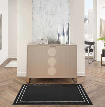 Hallway scene with Nourison Essentials Black Ivory rug, wood floors, and light wood cabinet.