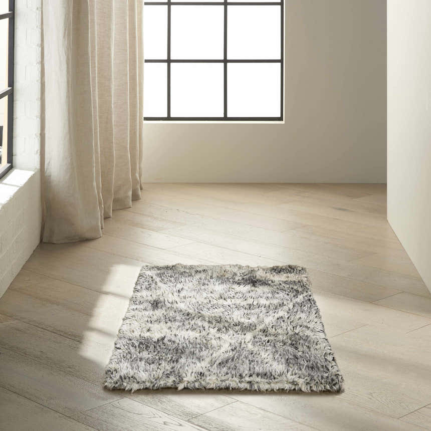 Minimalist room scene with a Calvin Klein San Antonio charcoal ivory shag rug on light wood floors near a window.