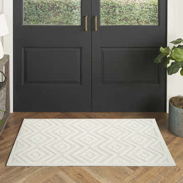Entryway with black door and Nourison Versatile Ivory White Modern Area Rug with geometric diamond pattern on wood floor.
