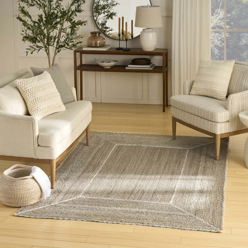 Living room scene with a Nourison Terrazzo Jute Natural Grey rug, sofa, chair, wooden console table, and light neutral decor.