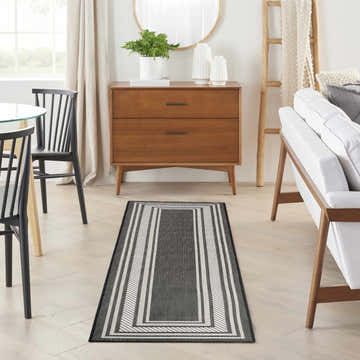 Dining room with a Nourison Horizon Black Modern Area Rug runner, wood accents, and neutral tones.