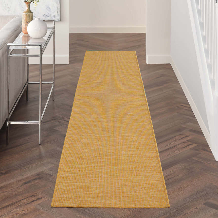 Hallway scene with a Nourison Positano Yellow runner rug on dark wood floors. Modern console table and white walls.