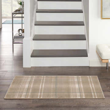 Entryway with Nourison Grafix Taupe Farmhouse Indoor Area Rug, dark wood floors, white stairs, and modern decor.