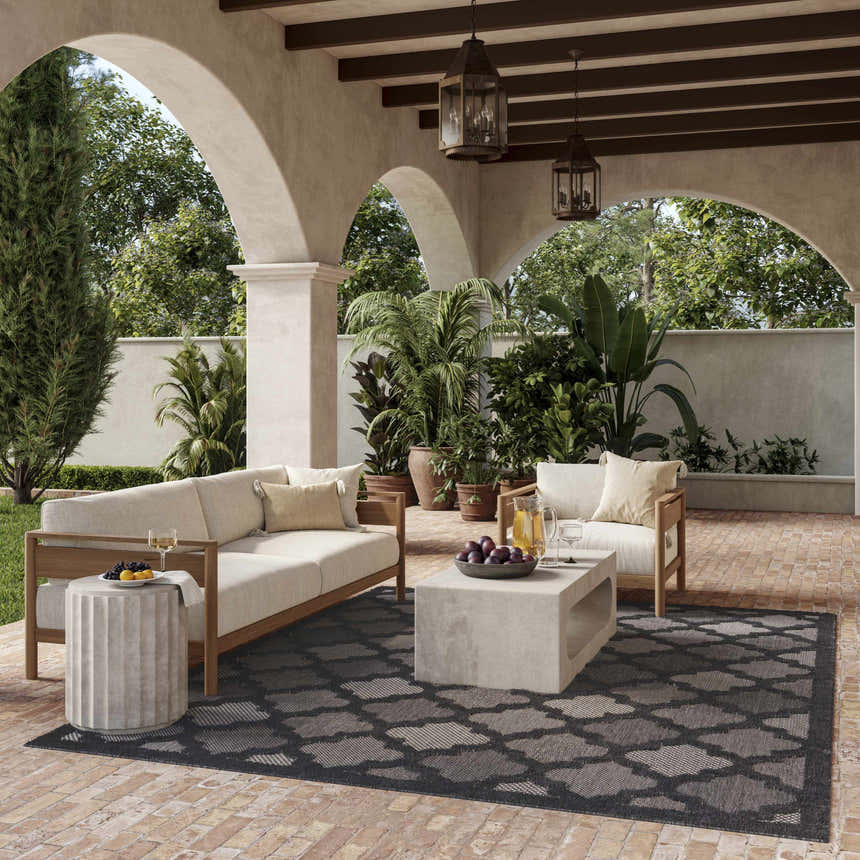 Outdoor patio scene with neutral furniture and Nourison Easy Care Charcoal Black Modern Area Rug.