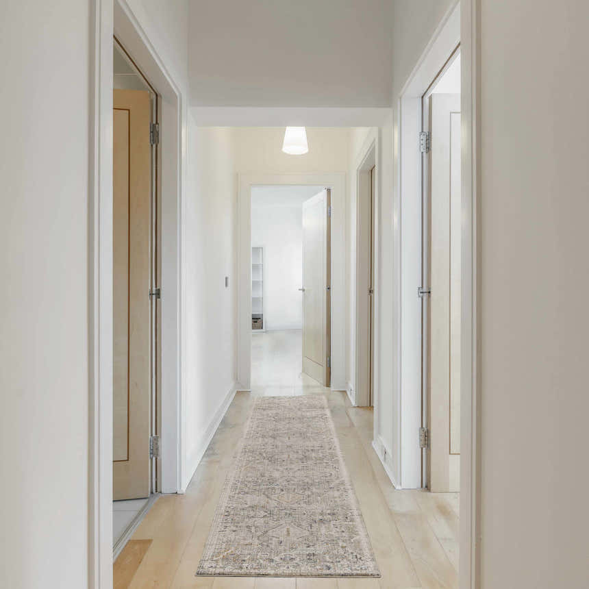 Hallway with a Nourison Lynx Ivory Taupe vintage runner rug on light wood floors, white walls and doors.