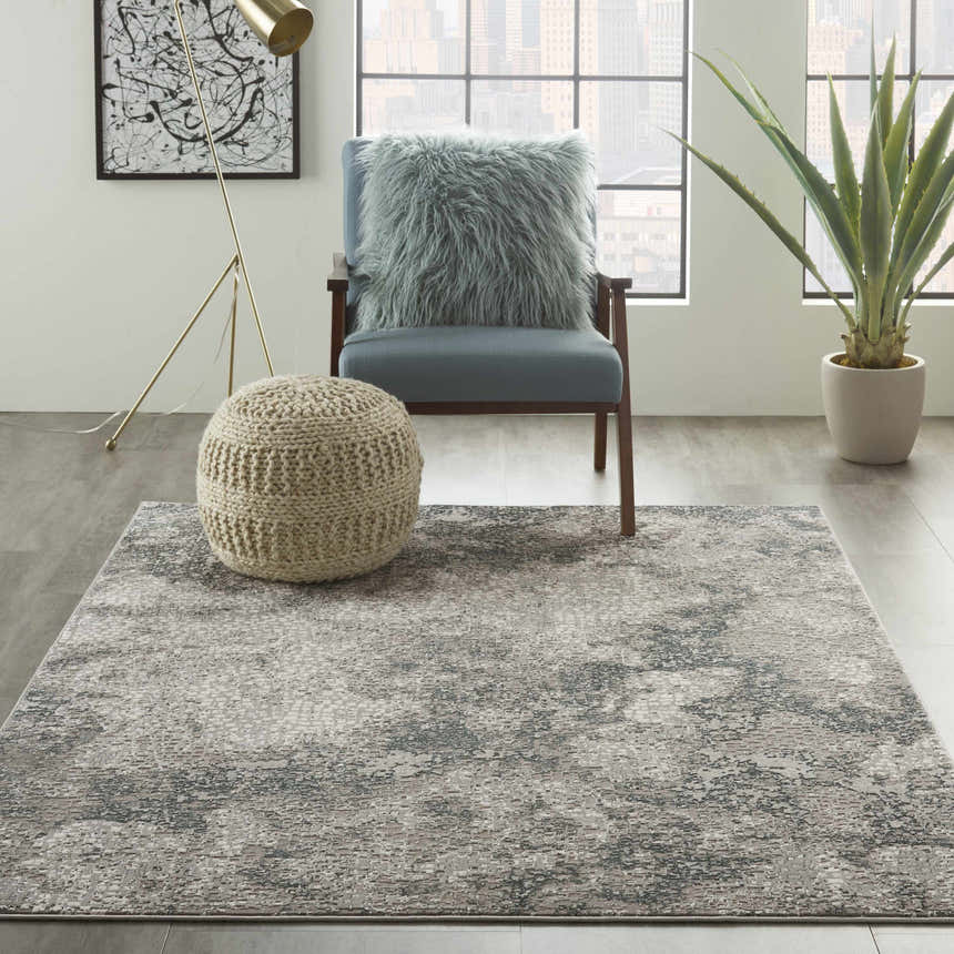 Modern living room with Michael Amini MA90 Uptown Grey rug, blue chair, knit pouf, and city view.