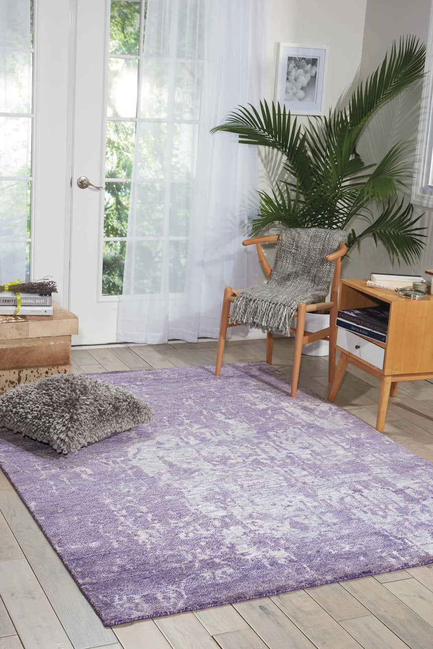 Sunlit room with Nourison Silk Shadows Amethyst rug, vintage style. Features a chair, side table, and a calming, neutral palette.