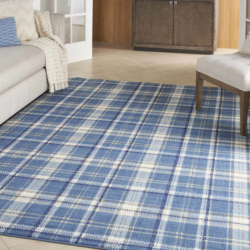 Living room scene with a blue plaid Nourison Grafix area rug, beige sofa, and white accent chair.