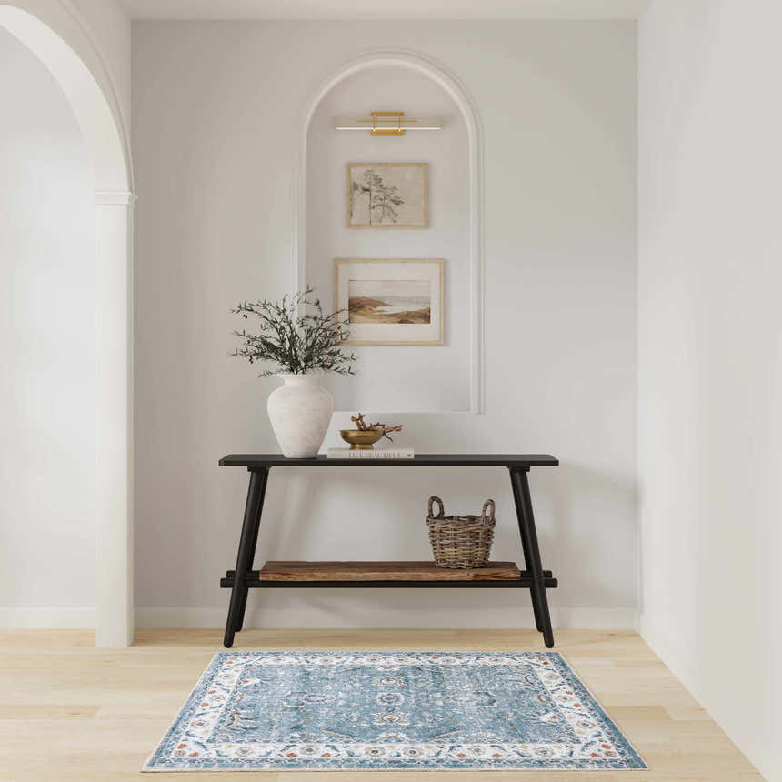 Entryway with black console table and Nourison Astra Blue Vintage Area Rug on light wood floor.