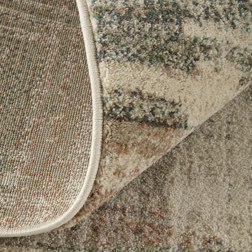 Close-up of the Feizy Eden Modern Abstract rug. Ivory, gray, and green tones with a subtle abstract pattern and textured pile. Fold