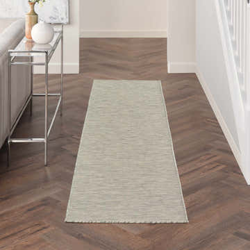 Hallway scene with Nourison Positano Light Grey runner rug on dark wood floors. Modern console table with vases.