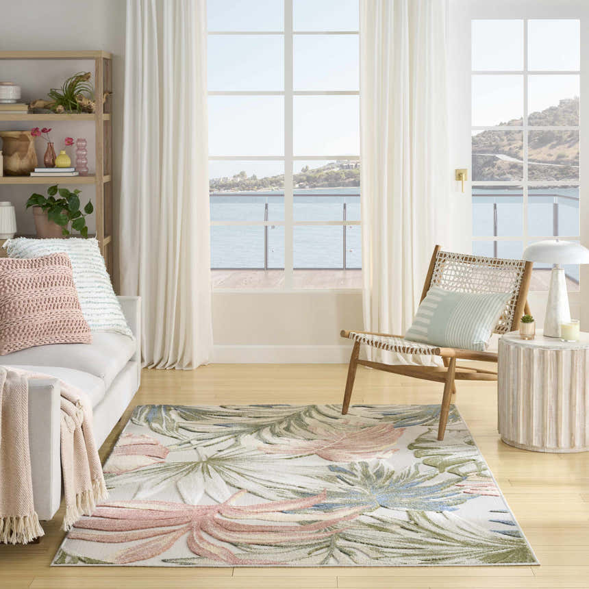 Coastal living room with a Nourison Aloha Ivory Green rug, white sofa, and ocean view.