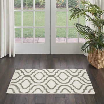 Entryway with Nourison Jubilant Ivory Green rug, dark wood floors, white french doors, and a potted palm.